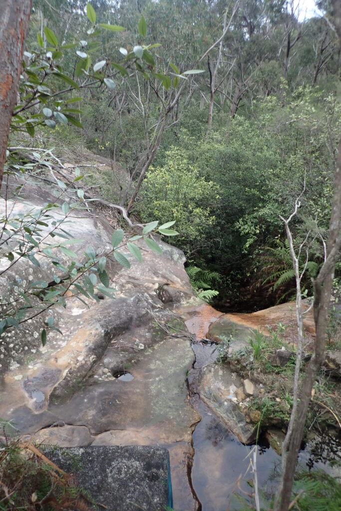 View down onto sandstone ledge and waterfall into lower creek.